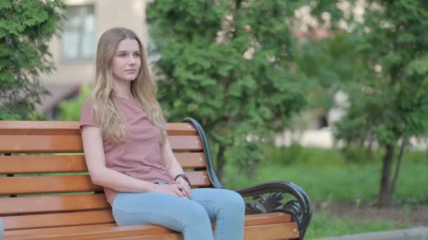 严肃的年轻女子坐在外面的长椅上 — 图库视频影像
