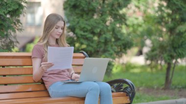 Genç Kadın Belgeleri Okuyor ve Laptop Kullanıyor