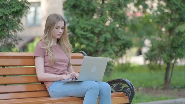 ベンチに座っている間にラップトップで働く若い女性 — ストック写真