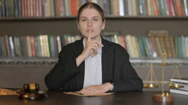 Female Lawyer with Finger on Lips in Office, Keep the Secret