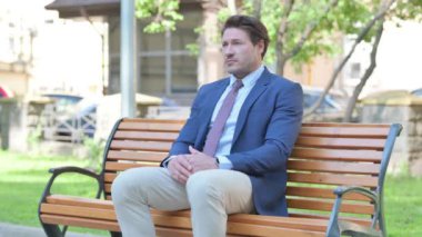 Orta yaşlı iş adamı ayağa kalktı ve Bench 'i açık havada bıraktı.