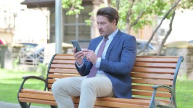 Smartphone 'da Başarı Kutlaması Yapan Orta Yaşlı İşadamı Bir Bankta Açık Otururken