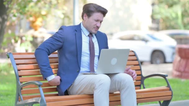 Biznesmen Korzystanie Laptop Bólem Pleców Podczas Siedzenia Zewnątrz — Wideo stockowe