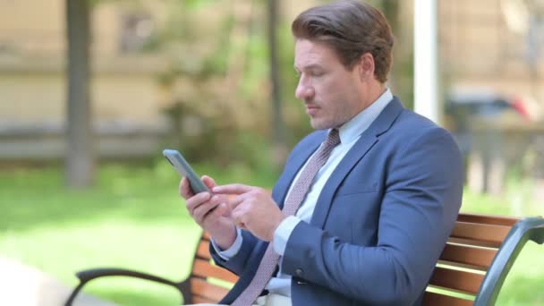 Πλευρική Άποψη Του Επιχειρηματία Χρησιμοποιώντας Smartphone Κάθεται Έξω Από Γραφείο — Αρχείο Βίντεο