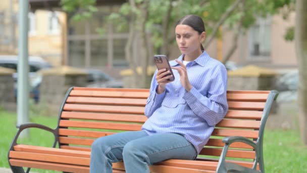 Hispanic Woman Shocked Loss Smartphone While Sitting Outdoor Bench — Stock Video