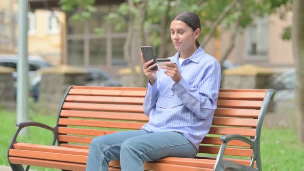 ヒスパニック女性は屋外で座っている間 電話でオンラインショッピングをする — ストック動画