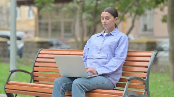 坐在室外时使用背痛手提电脑的西班牙妇女 — 图库视频影像