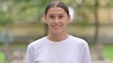 Gülümseyen, kendine güvenen, dışarıda dikilen İspanyol kadın.