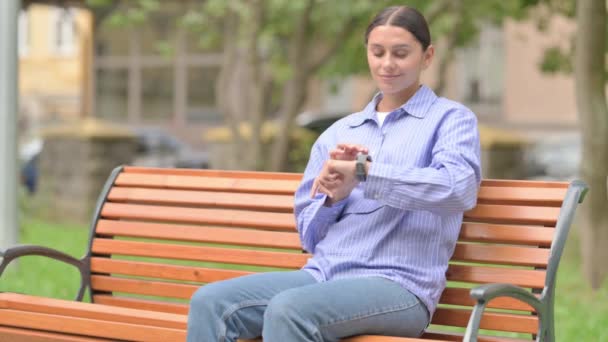 西班牙妇女坐在户外时使用智能手表 — 图库视频影像