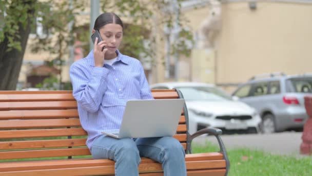 拉丁美洲妇女在电话交谈和使用笔记本电脑室外 — 图库视频影像