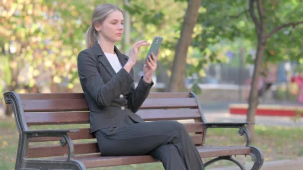 一位女商人坐在外面的长椅上 因电话损失而惊慌失措 — 图库视频影像