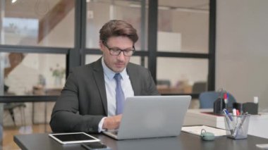 Ofiste Dizüstü bilgisayarla çalışırken Kameraya Bakan İşadamı