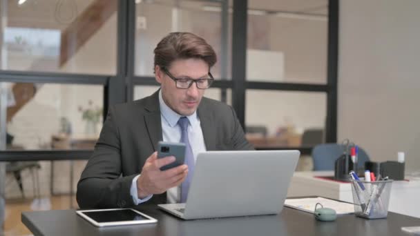 Бизнесмен Работающий Над Ноутбуком Использующий Смартфон — стоковое видео