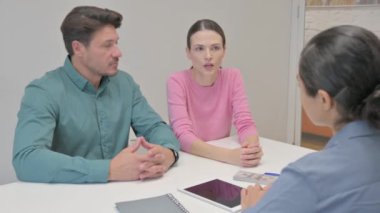 Genç çift ofiste Hintli kadınla konuşuyor.