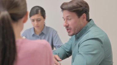 Ofiste takım arkadaşlarıyla konuşan kızgın adam.