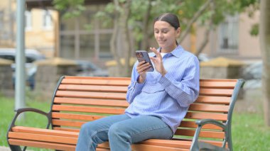 Bir bankta otururken Smartphone kullanan İspanyol Kadın