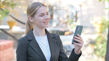 İş kadını telefonda görüntülü konuşma yapıyor.