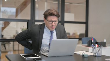 Ofiste dizüstü bilgisayar kullanırken Sırt Ağrısı çeken İşadamı