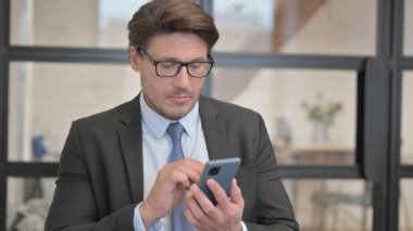 Ofiste otururken telefonu kullanan iş adamı