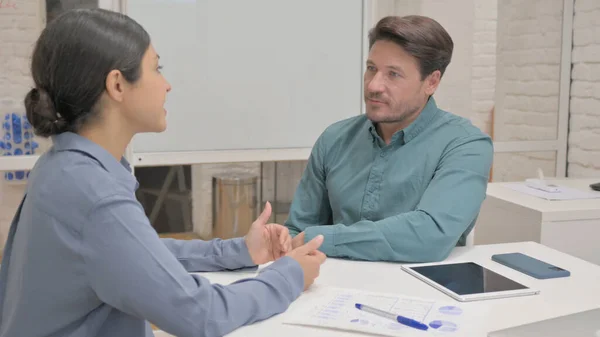 Middle Aged Man in Conversation with Indian Woman in Office