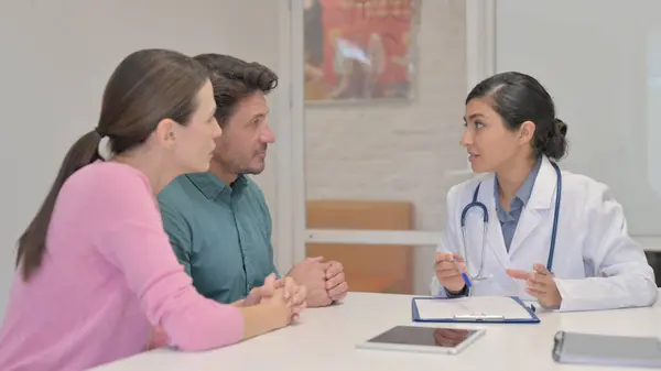 Indian Doctor Talking with Couple in Hospital