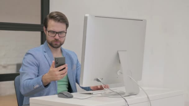 Homem Jovem Usando Smartphone Para Trabalhar Desktop — Vídeo de Stock