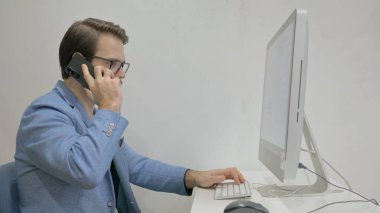 Masaüstünde Çalışırken Telefonda Konuşan Orta Yaşlı Adam