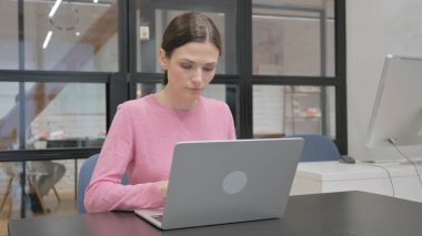 Ofisteki dizüstü bilgisayarda çalışan genç kadın.