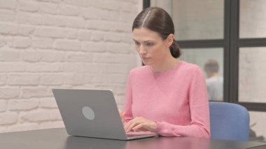 Ofisteki dizüstü bilgisayarda çalışan genç kadın.