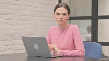 Sıradan bir kadın çalışırken kameraya bakıyor.