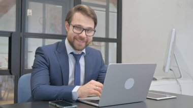 Genç İşadamı Bilgisayarda Çalışırken Kameraya Gülümsüyor