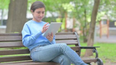 Açık havada oturan Hintli kadın dijital tablet kullanıyor