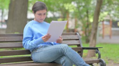 Açık havada oturan Hintli Kadın Belgeleri Okurken Kutluyor