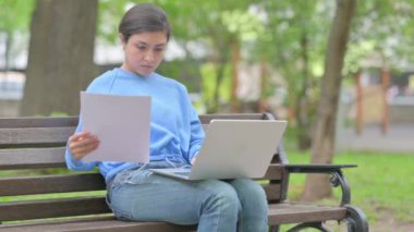 Açık havada oturan Hintli Kadın Belgeler ve Laptop üzerinde çalışıyor