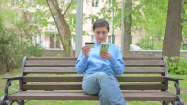 Bankta otururken Hintli Kadın İnternetten Telefonla Alışveriş Yapıyor