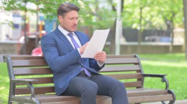 İş adamı Bench 'te otururken İş Raporundan Şok Oldu