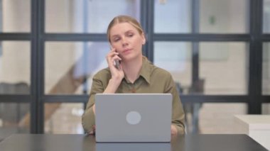 Yetişkin Kadın Laptop 'ta çalışırken telefonda konuşuyor