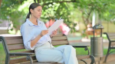 Bench 'te otururken Karışık Irk Kadını Belgeleri Okuyor