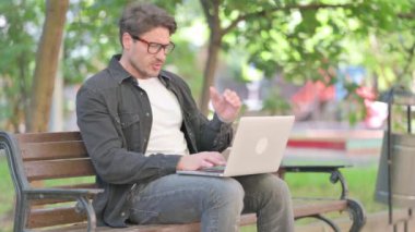 Migreni olan orta yaşlı bir adam laptop kullanıyor.