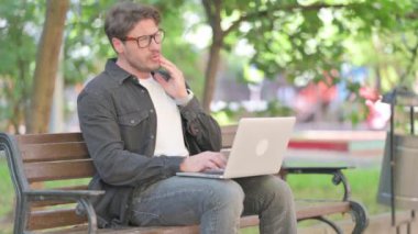 Dişleri ağrıyan orta yaşlı adam laptop kullanıyor.