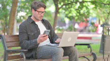 Smartphone ve Laptop üzerinde çalışan orta yaşlı bir adam.