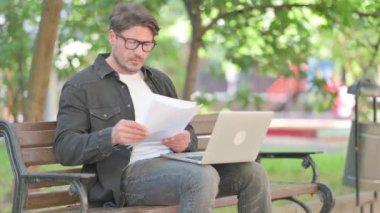 Belgeler ve laptopla çalışan orta yaşlı bir adam.