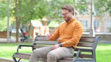 Migreni olan gergin genç adam dışarıda oturuyor.