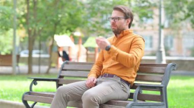 Hasta genç adam dışarıda otururken öksürüyor.