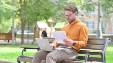 Laptop 'la evrak işi yapan genç adam.
