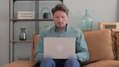 Laptop 'ta çalışan dalgın orta yaşlı adam.