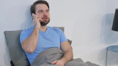 Kızgın Orta yaşlı adam yatakta telefonla konuşuyor.