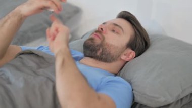 Kızgın Orta yaşlı adam yatakta yatarken telefonla konuşuyor.