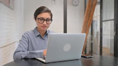 Ofiste Dizüstü bilgisayarla çalışırken kameraya bakan Hintli iş kadını