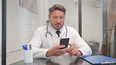 Yetişkin Doktor, hastanede akıllı telefon kullanıyor.